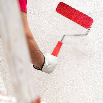 Bras droit main gant tenant pinceau mur blanc