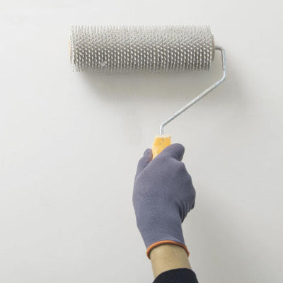Main gant travaux gris passe rouleau mur blanc