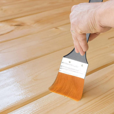 Main tenant pinceau passant vernis bois clair
