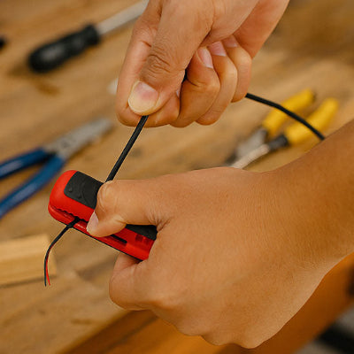 Cable dans pince a denuder en action entre deux mains