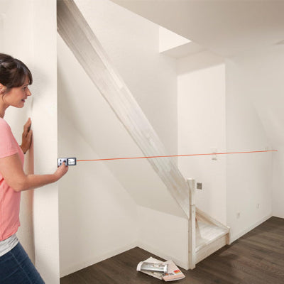 Femme-prends-mesure-pièce-vide-escalier-avec-télémètre-laser