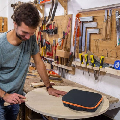 Homme souriant barbu ponce arrête planche bois ronde boite posée sur ouvrage