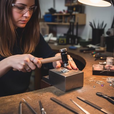 Jeune fille lunettes protections tape avec marteau boitier metal sur etabli arrondi