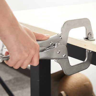 Main jeune tenant la poignée d'une pince sur bord table