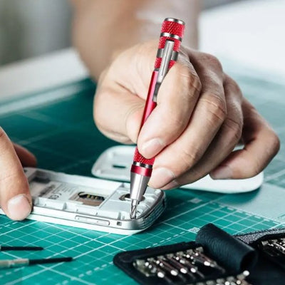 Tournevis rouge tenu main homme intérieur tel portable tapis cadrié vert