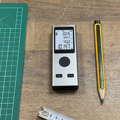 Telemèere laser gris sur plan de travail côté crayon jaune illustre sa petite taille.